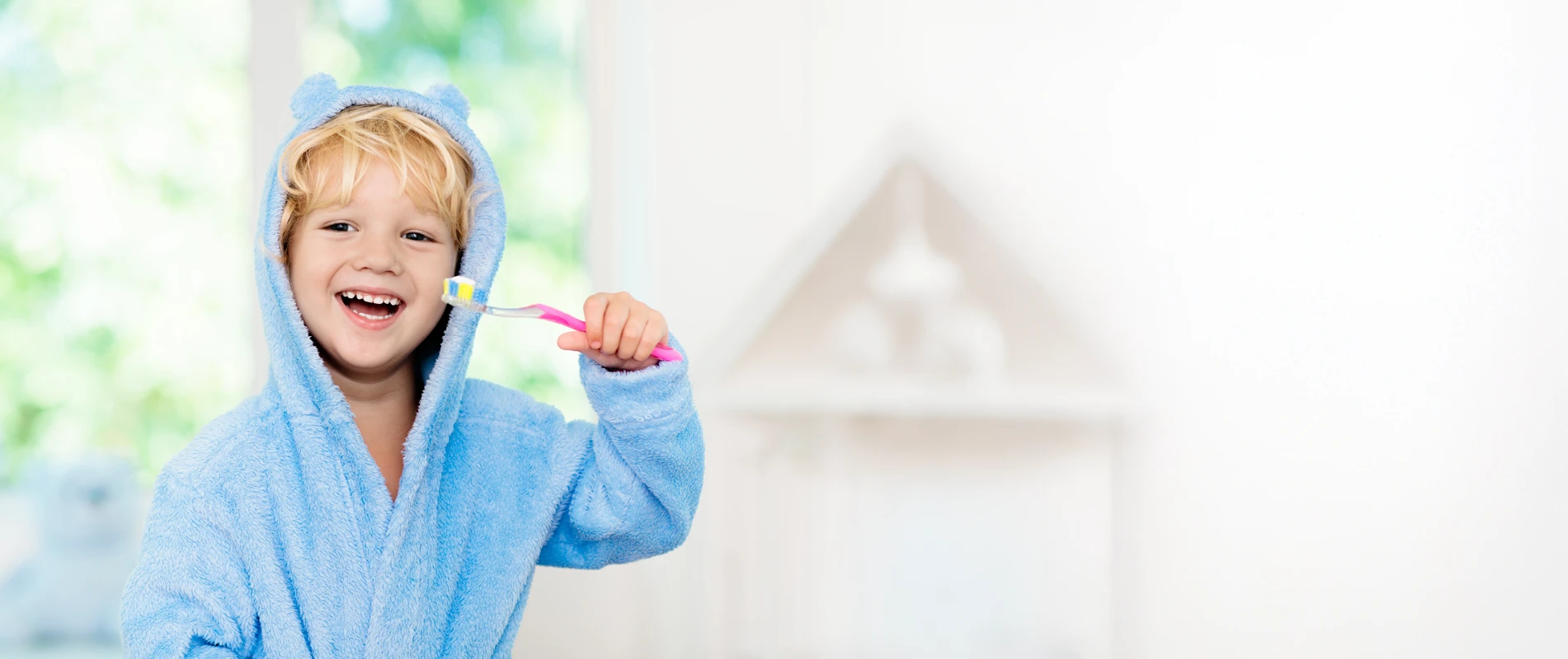 A young boy in a fuzzy bathrobe brushing his teeth before bed